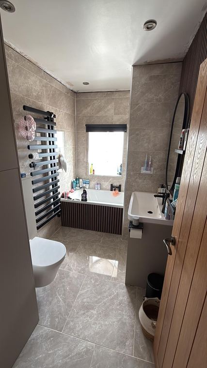Bathroom in stone-effect tiling with a black towel radiator
